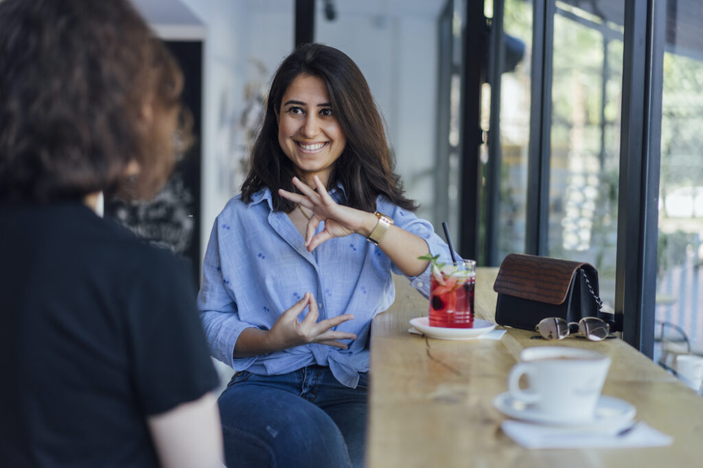 A sign language conversation between two people with beverages.