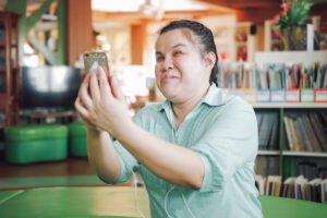 A photo of a blind and disabled person enjoys using her mobile device in a library.