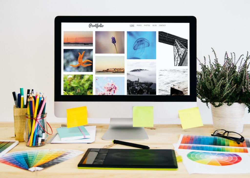 A photo of a computer monitor covered in post-it notes shows colourful photo thumbnails on a busy desk.