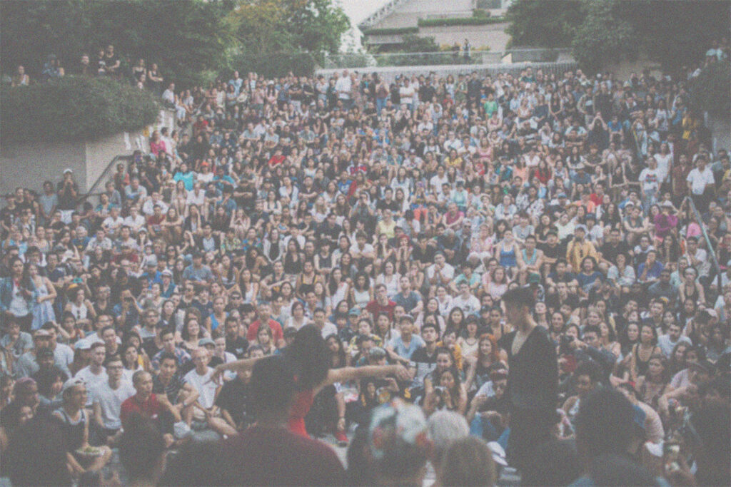 Huge audience on stairs at outdoor venue watches dance performance in Vancouver.